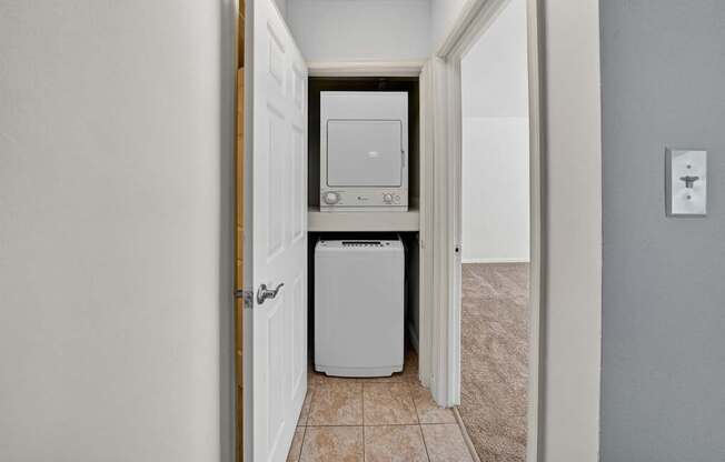 A white washing machine and dryer is in a hallway.