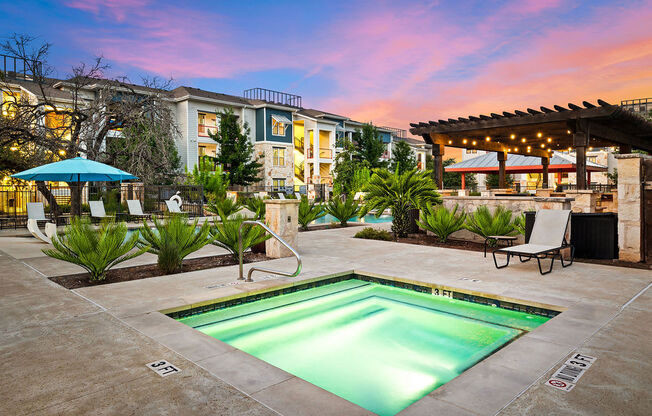 a swimming pool with a building in the background at sunset