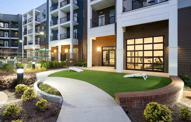 an exterior view of an apartment building with green grass and a sidewalk
