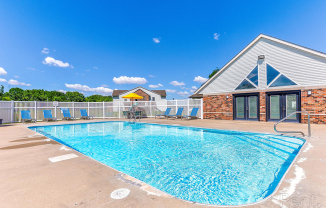 our resort style swimming pool is in front of our building with chairs and a building