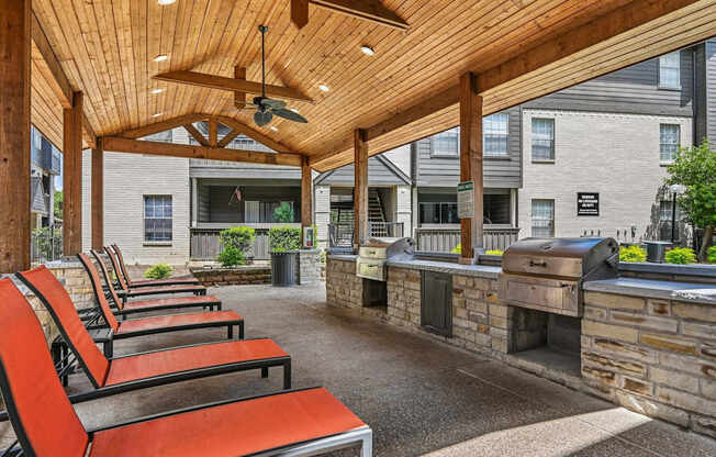 A patio with red chairs and a fireplace.