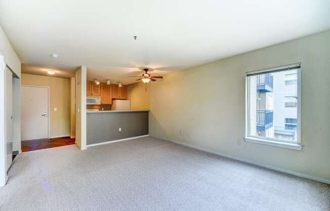 the living room and kitchen of an empty house with a ceiling fan