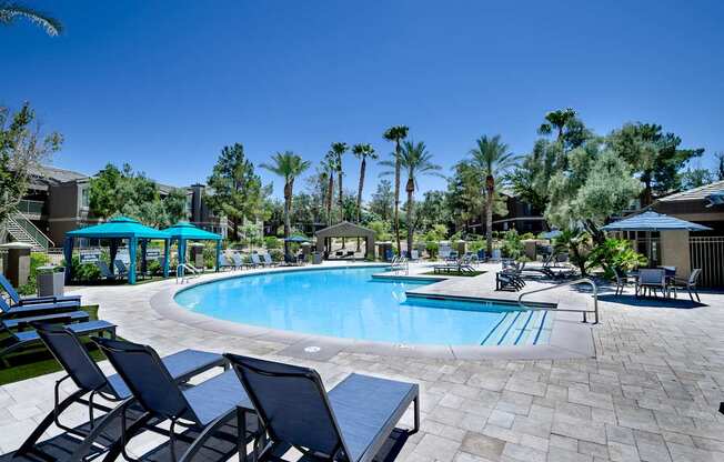 A pool surrounded by chairs and palm trees.