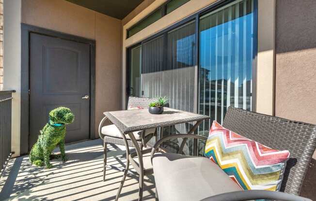 a dog sitting on a balcony with a table and chairs