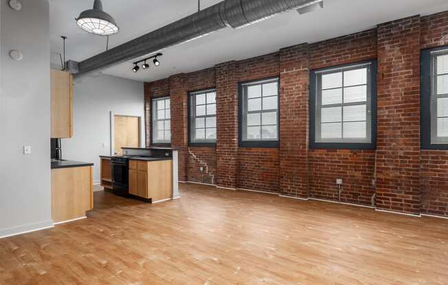 an empty living room with a brick wall and wood floors