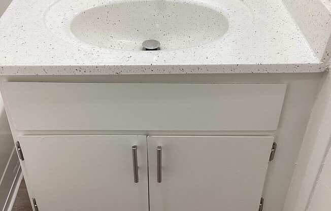 A white bathroom sink with a white cabinet below it.