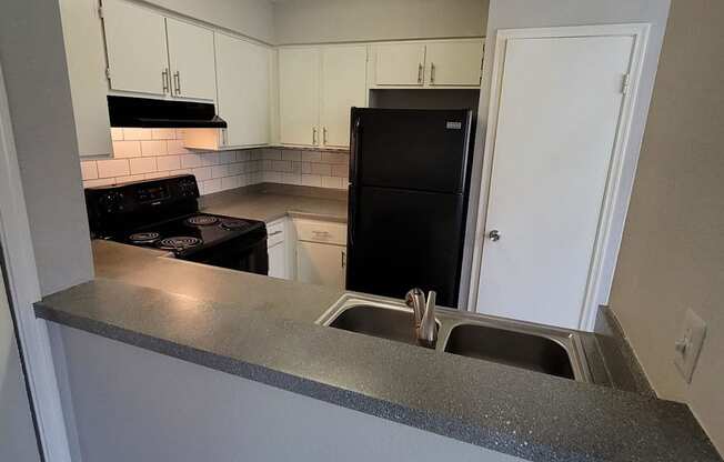 a kitchen with a sink and a black refrigerator