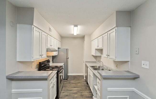 A kitchen with white cabinets and a grey countertop.