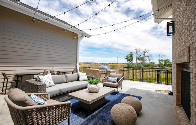 A patio with a sofa, chairs, and a table with a potted plant on it.
