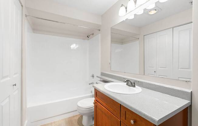 A white bathroom with a toilet, sink, and mirror.