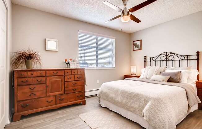 A bedroom with a bed, dresser, and ceiling fan at Mountain Vista Apartments, Lakewood, 80228