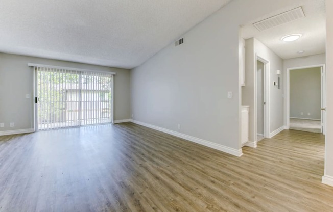 an empty living room with hardwood floors and a large window