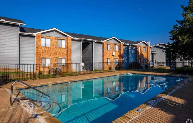 a swimming pool in front of apartments with a pool