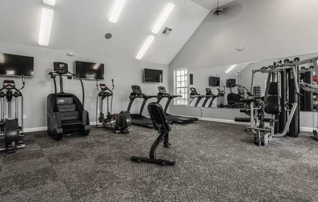 a gym with cardio machines and televisions in a building