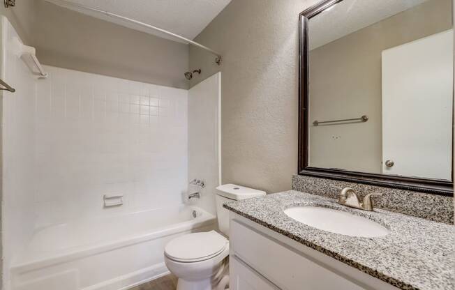 a light colored bathroom with sink and toilet and shower with white tub at Veridian at Sandy Springs