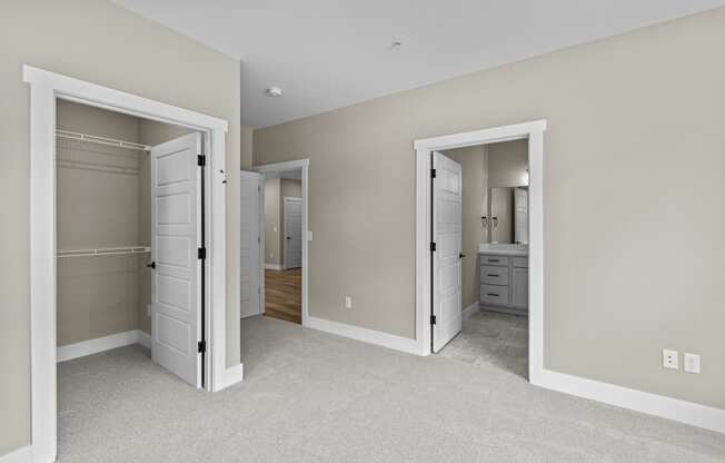 a bedroom with two closets and a bathroom in the background