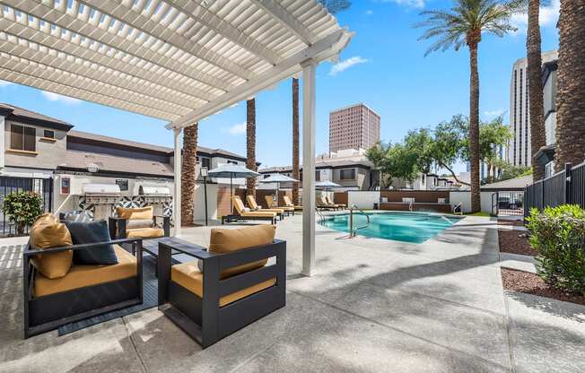 A patio with a pool and a white pergola.