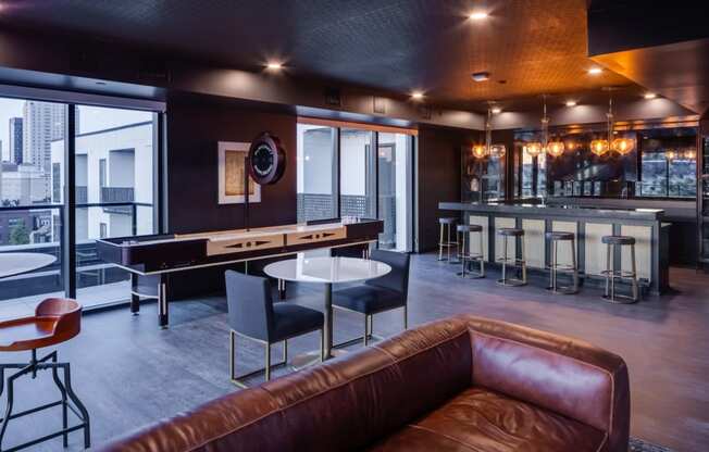 a living room with a brown leather couch and a bar with tables at Maven on Broadway, Rochester, 55904