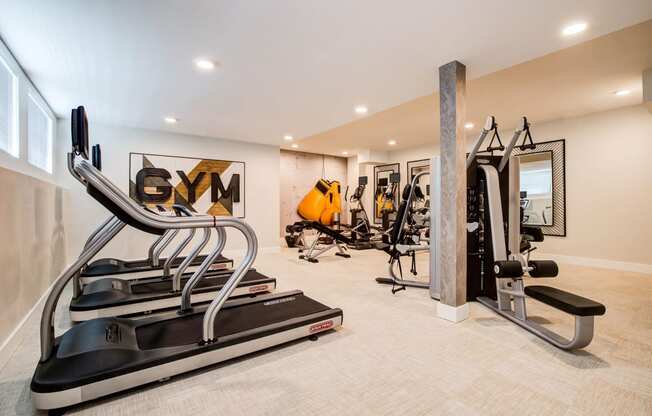 Gym with Ellipticals, Gaint Gym Sign on Wall, Weight Machines and Mirros on Wall