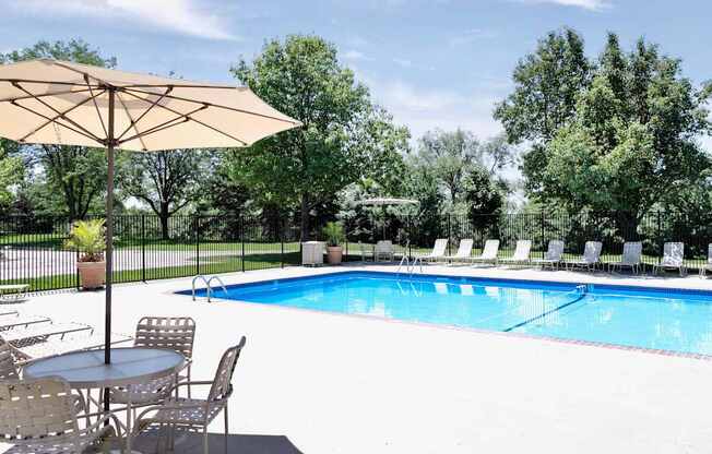 A pool with chairs and an umbrella. at Tranquility Pointe, Nebraska, 68164
