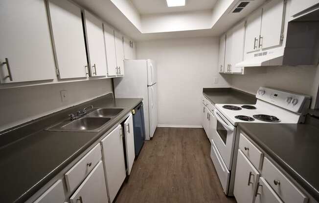 an empty kitchen with white cabinets and appliances and a sink