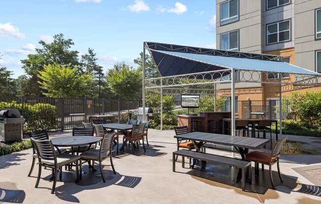 a patio with tables and chairs and a grill