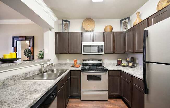 A kitchen with a stove, sink, and refrigerator.