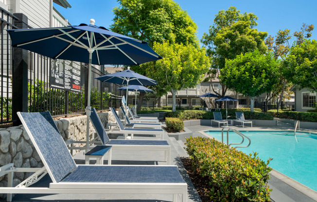a pool with lounge chairs and umbrellas next to a building
