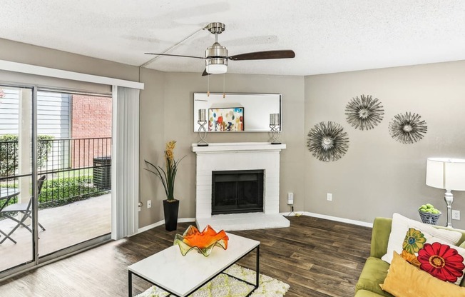 Model living room with a fireplace and a sliding glass door to patio at Hunters Chase in Austin, TX