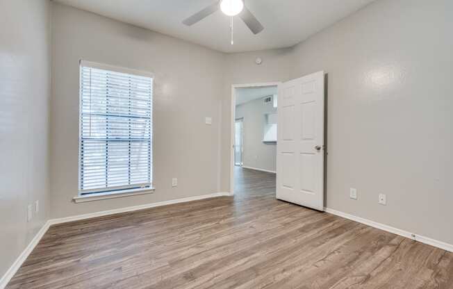 an empty living room with a white door and a ceiling fan