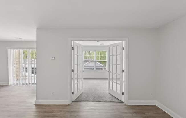 A room with a white door and a grey carpet.