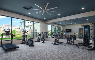 A spacious gym with a variety of equipment including treadmills, elliptical machines, and weight racks.