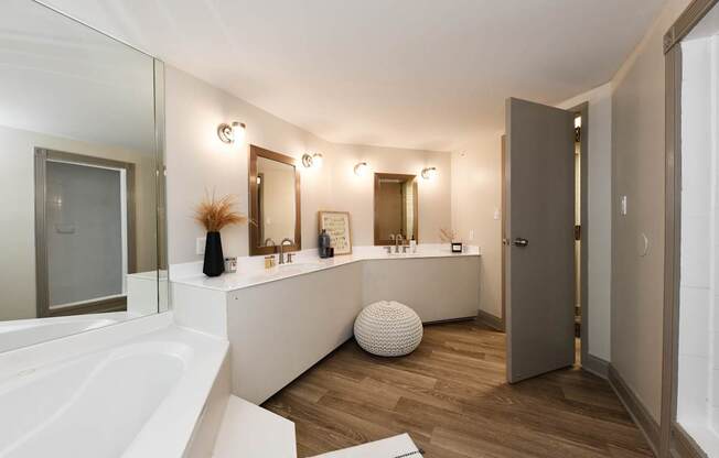 A white bathroom with a large tub and a vanity with a mirror.