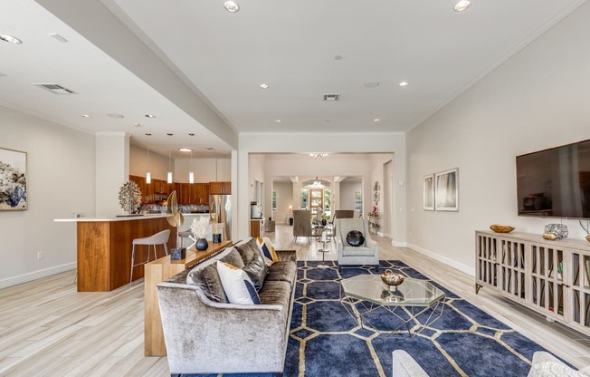 A spacious living room with a blue rug and a grey sofa.