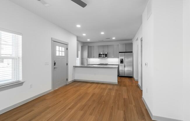 a living room and kitchen with white walls and wood floors