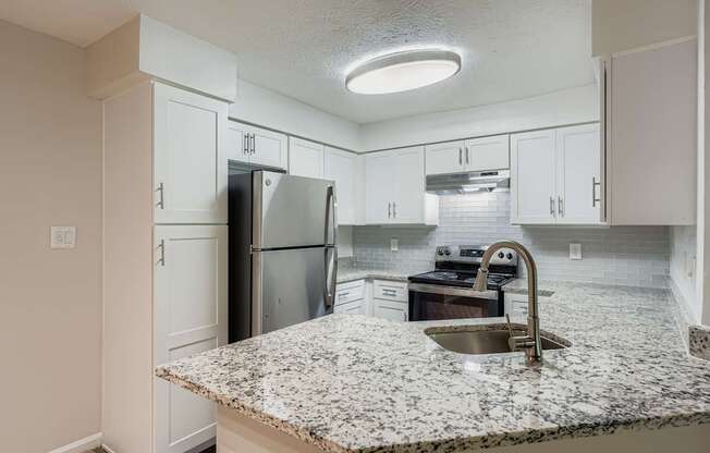 A kitchen with granite countertops and white cabinets.