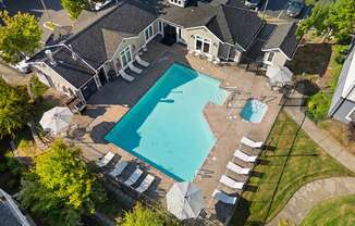 an aerial view of a swimming pool and patio with umbrellas and a house