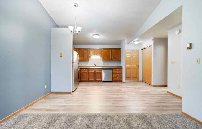 A kitchen area with wooden cabinets and a grey rug on the floor.