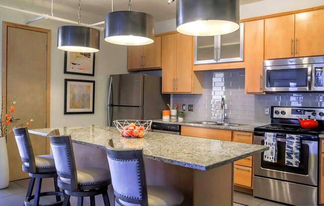 A kitchen with a granite countertop and stainless steel appliances.