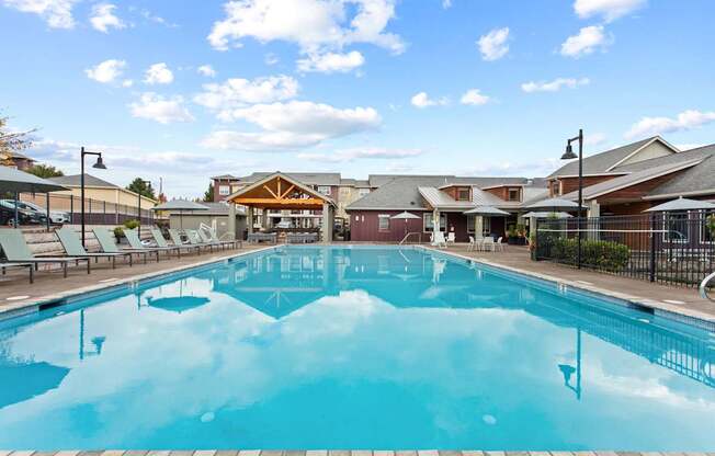 A large outdoor swimming pool with a wooden deck and lounge chairs.