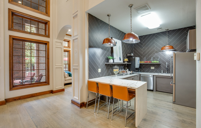 View of Community Kitchen with Stainless Steel Appliances, Hanging Lights, and Counter Stools at Raveneaux Apartments