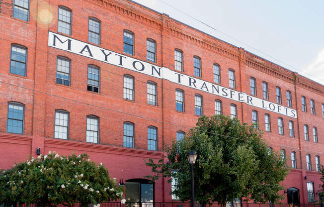 a large brick building with a sign on the side of it at Mayton Transfer Lofts, Petersburg Virginia