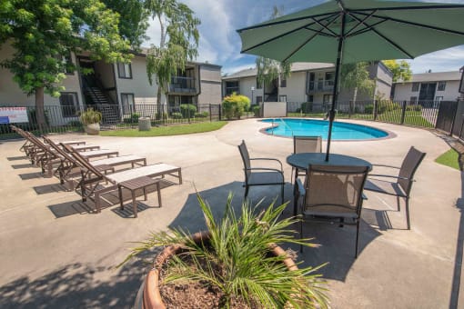 A large pool and patio with chairs and umbrellas