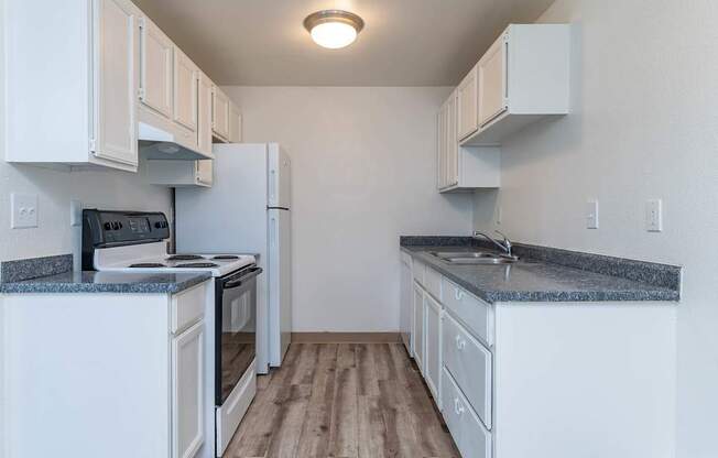 A kitchen with white cabinets and a granite countertop.