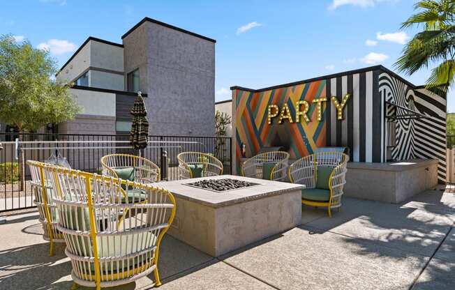 a patio with chairs and a fire pit in front of a building