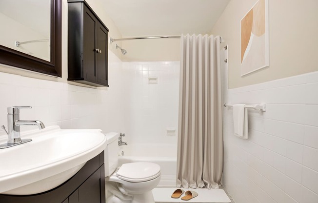 A bathroom with a white sink, toilet, and a shower with a grey curtain.
