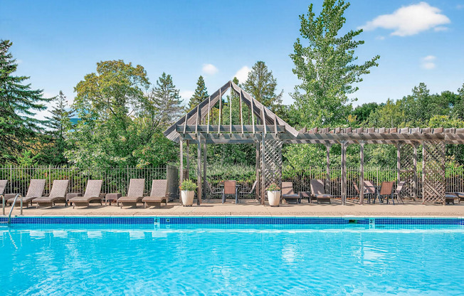 A pool with a wooden structure and chairs around it.
