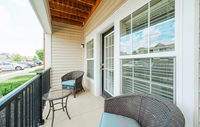 a porch with two chairs and a table and a large window