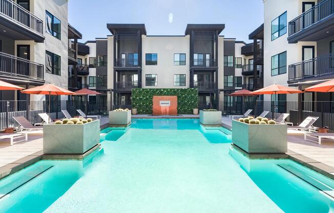A striking pool courtyard at Modera Higley Commons, where crisp lines, resort-style seating, and a serene water feature define the outdoor experience.