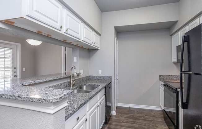 an empty kitchen with white cabinets and granite counter tops